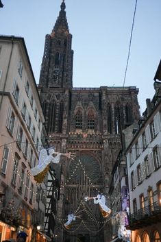 an old cathedral is lit up with christmas lights and angel decorations in the foreground