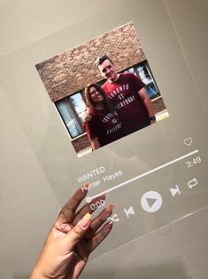 a hand is holding up a glass frame with an image of a man and woman on it