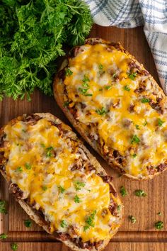 two pieces of bread topped with cheese and parsley on top of a cutting board