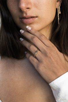 a woman with freckles and rings on her finger posing for the camera while wearing a white dress