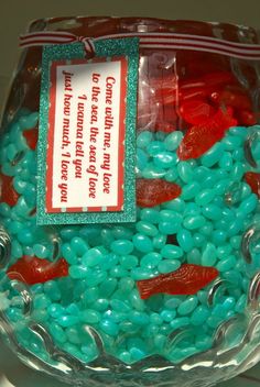 a glass bowl filled with blue and red candies next to a sign that says don't touch the fish