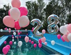 balloons are floating in the water next to an outdoor pool with numbers and streamers