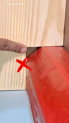 a person with their finger on the edge of a red piece of wood that has been cut in half