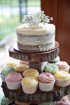 a three tiered cake with cupcakes on it