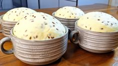 four mugs filled with cake sitting on top of a wooden table