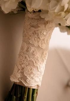 the bridal bouquet is adorned with lace and white carnations, as well as flowers