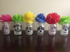 six jars with tissue paper flowers in them sitting on a wooden table next to a wall