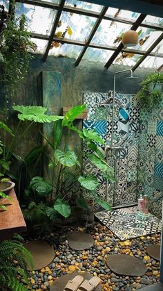 a bathroom with green plants and rocks in the floor, along with a glass roof