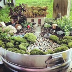 a pot filled with lots of green plants and small houses in the middle of it