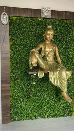 a golden buddha statue sitting on top of a wooden bench in front of a green wall