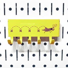 a yellow toy train sitting on top of a white wall next to black and gray dots