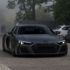 an audi sports car driving down the road in front of other cars on a foggy day