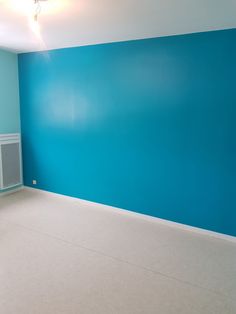 an empty room with blue walls and white floors