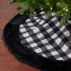 a black and white plaid hat sitting on top of a wooden table next to a christmas tree