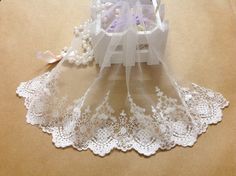 a white lace doily on top of a table next to a box with flowers