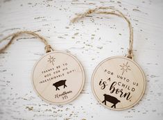 two wooden christmas ornaments hanging from twine on a white background with words that say, for unto us incredible gift is born