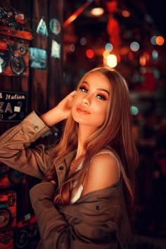 a beautiful young woman leaning against a wall with her hand on her head and looking at the camera