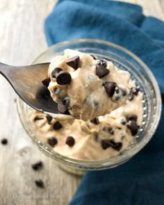 a spoon full of ice cream with chocolate chips on it and a blue napkin in the background