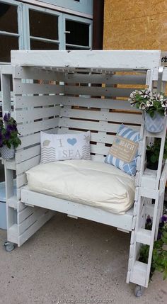 a bench made out of wooden pallets with pillows and flowers on the bottom shelf