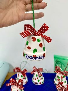 a hand holding a christmas bell ornament with red, white and green polka dots on it