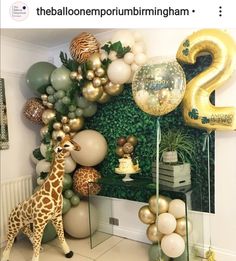 a giraffe standing in front of a wall with balloons