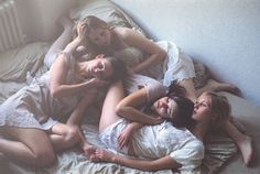 four women laying on a bed together in the middle of their nightgowns