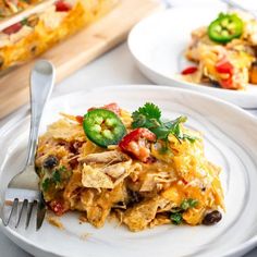 a white plate topped with mexican food next to a fork and serving dish on a table