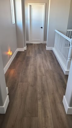 an empty room with wood flooring and white trim on the walls, stairs and railings