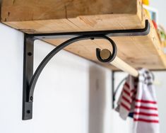 a wooden shelf with metal brackets and hooks hanging from it's sides on a wall