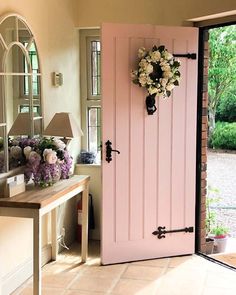 a pink door with a wreath on the front and side panels is opened to reveal a hallway