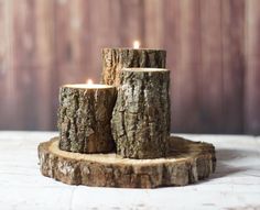 three wooden candles are sitting on a piece of wood that has been cut in half