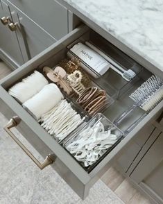 an open drawer filled with lots of white dishes and utensils on top of a marble countertop