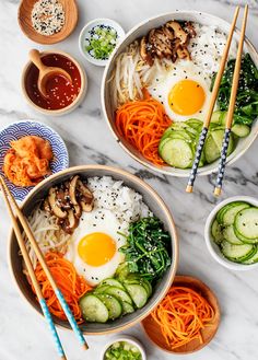 two bowls filled with different types of food and chopsticks on top of a table