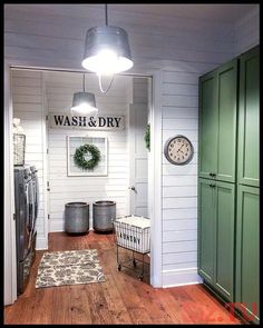 a wash and dry room with green cabinets, baskets and a clock on the wall