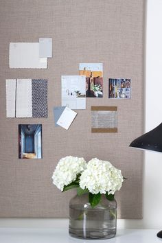 a vase filled with white flowers sitting on top of a table next to a wall