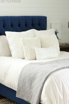 a bed with white sheets and pillows on it