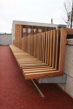 a long wooden bench sitting on top of a red carpeted floor next to a wall