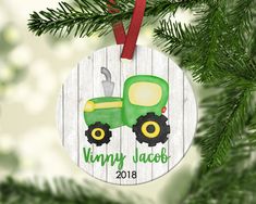 a personalized ornament hanging from a christmas tree with a tractor on it