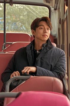 a young man sitting in the back of a bus with his hand on the handle