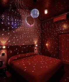 a red bed in a room with disco lights on the walls and ceiling above it