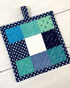 a blue and white patchwork square with polka dots on the side, sitting on a wooden surface