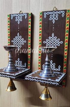 two metal candlesticks sitting next to each other on top of a wooden wall