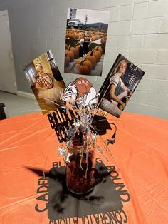 an orange table cloth with some pictures on it and a vase full of flowers in the center