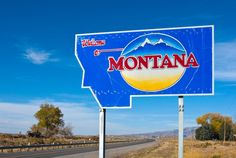 a blue sign with the word montana on it in front of a road and trees