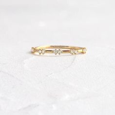 a yellow gold ring with three diamonds on the top and bottom, sitting on a white surface