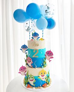 a three tiered cake decorated with blue and white balloons