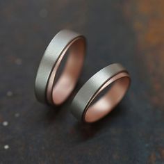 two wedding rings sitting on top of a black surface with one ring in the middle