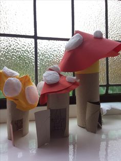 three little houses made out of paper sitting on top of a table next to a window