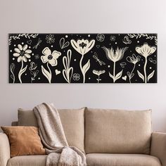 a living room with a couch and large painting on the wall above it that has flowers in black and white