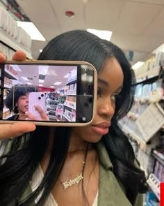 a woman taking a selfie in a store with her cell phone up to her face